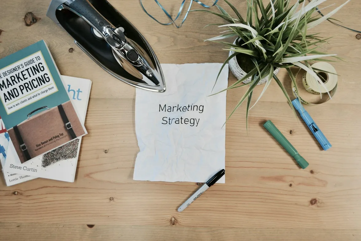 Bureau vu de dessus avec une feuille de stratégie marketing, des livres de design et des feutres