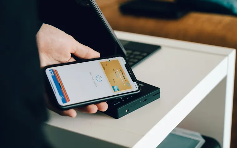 Main tenant un smartphone qui affiche une carte numérique au-dessus d'un terminal sans contact